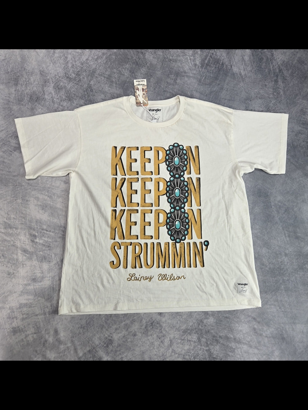 The Wrangler x Lainey Wilson Keep On Strummin' Tee is an oversized cream cotton